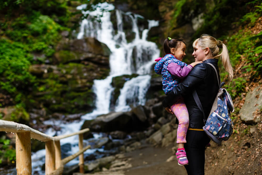 Mother holding daughter in front of a waterfall during a North Carolina family vacation in Highlands